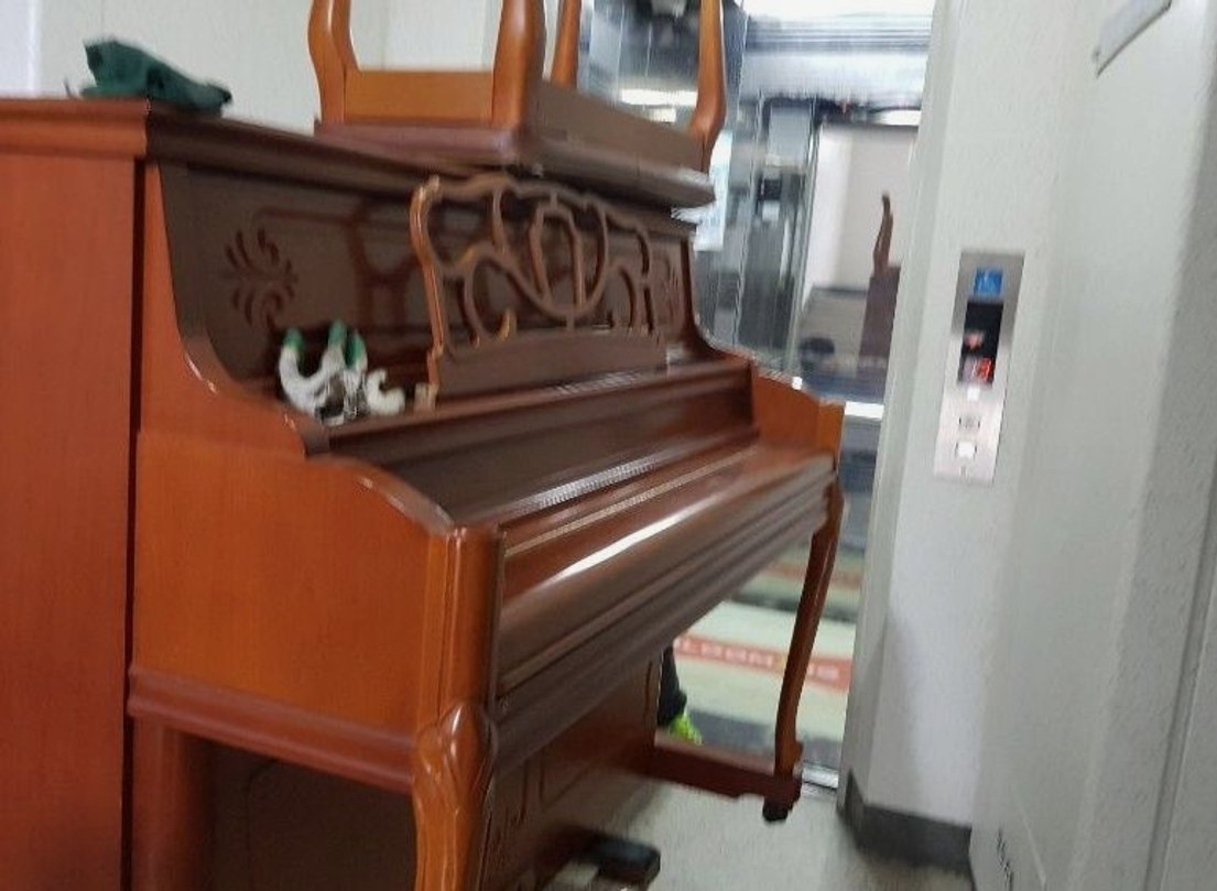 엘리베이터 앞까지 옮겨진 갈색 업라이트 피아노